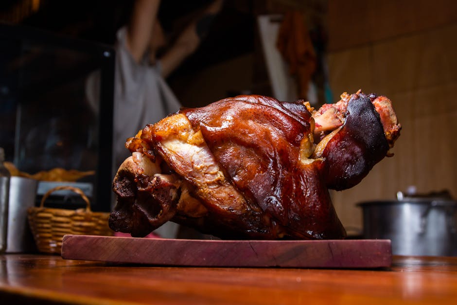 A rustic wooden platter displaying a variety of cured meats, including thinly sliced salami and ham, arranged in neat overlapping rows. The platter also features fresh green and white grapes, clusters